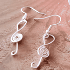 Silver treble clef earrings on a wooden surface