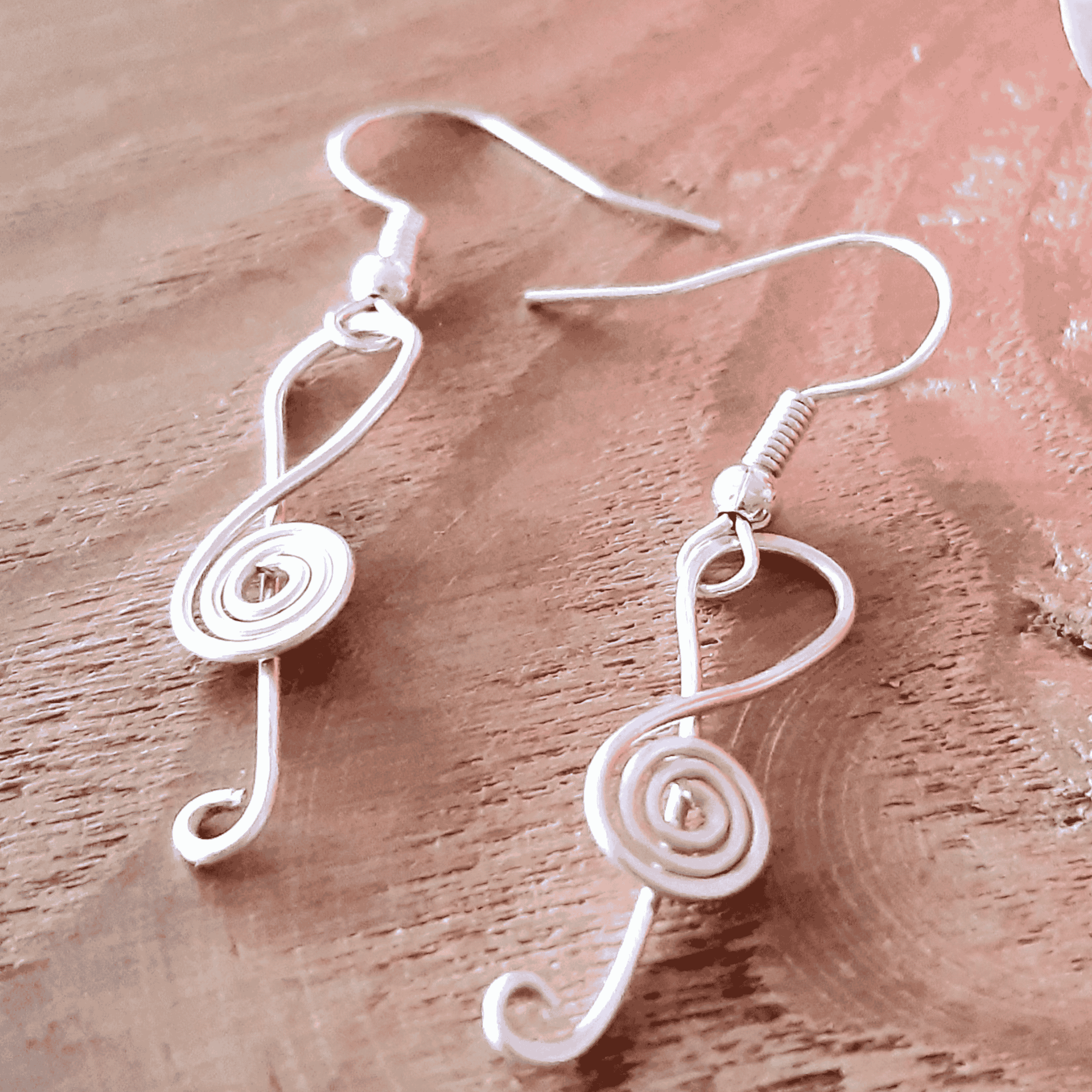Silver treble clef earrings on a wooden surface