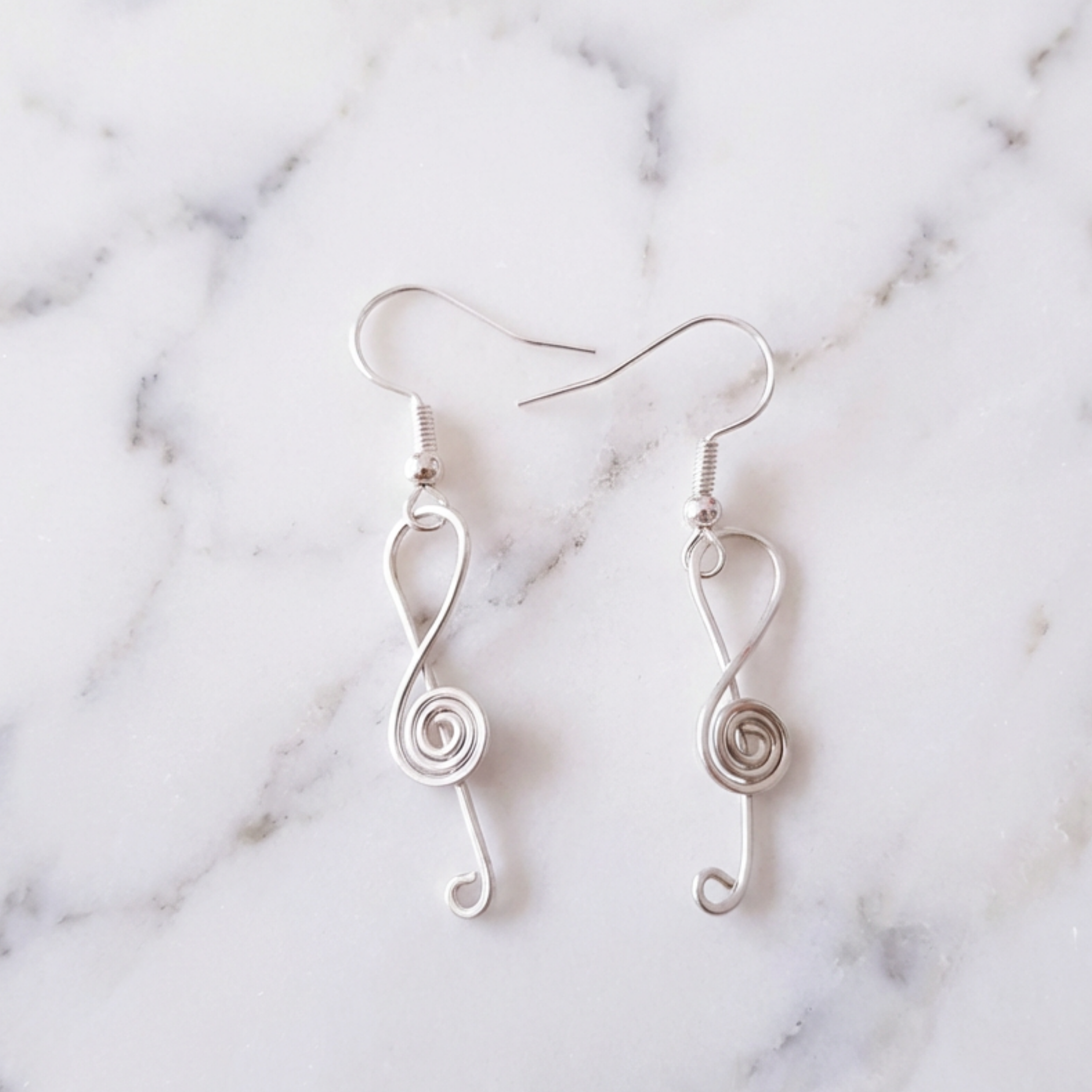 Silver spiral earrings on a marble background