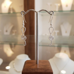 Silver spiral earrings on a display stand with a blurred background
