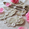 Silver spiral necklace on a leafy background with pink flowers