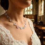Bride wearing a silver spiral necklace with a stained glass window in the background