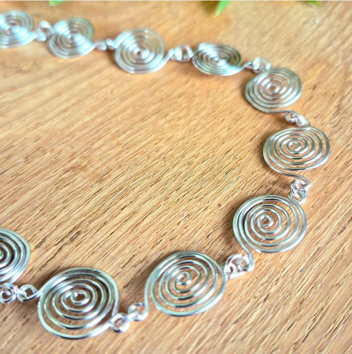 Silver spiral necklace on a wooden surface