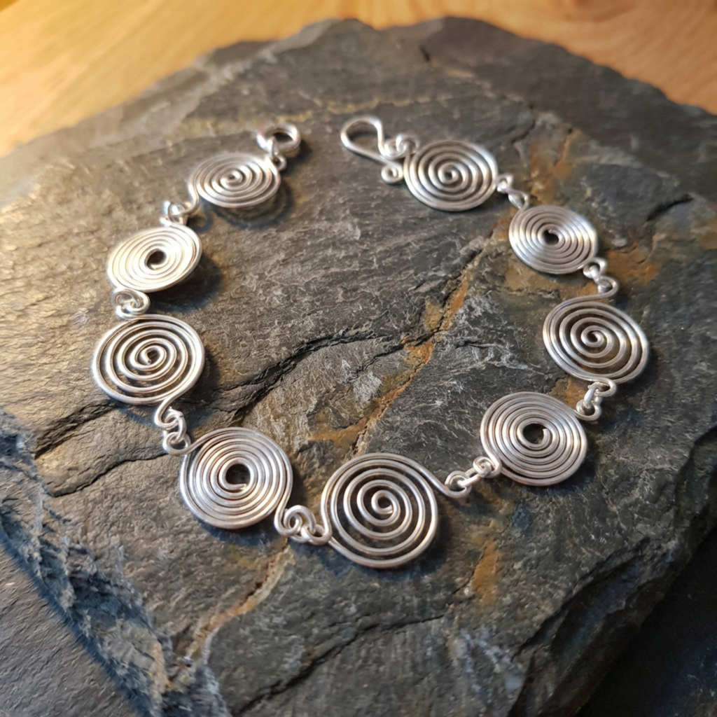 Silver spiral bracelet on a dark stone surface