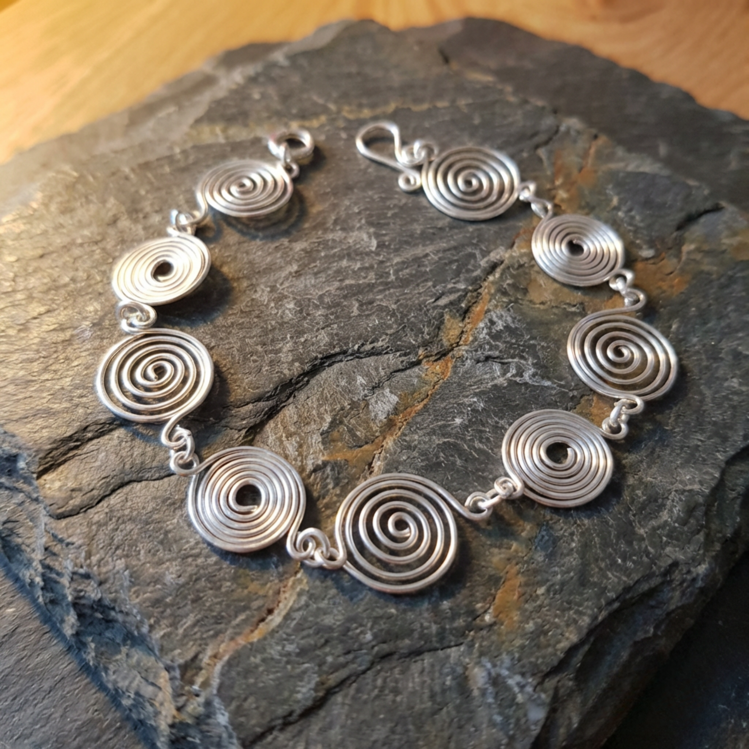 Silver spiral bracelet on a dark stone surface