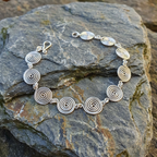 Open silver spiral bracelet, full view on a stone background, handmade UK