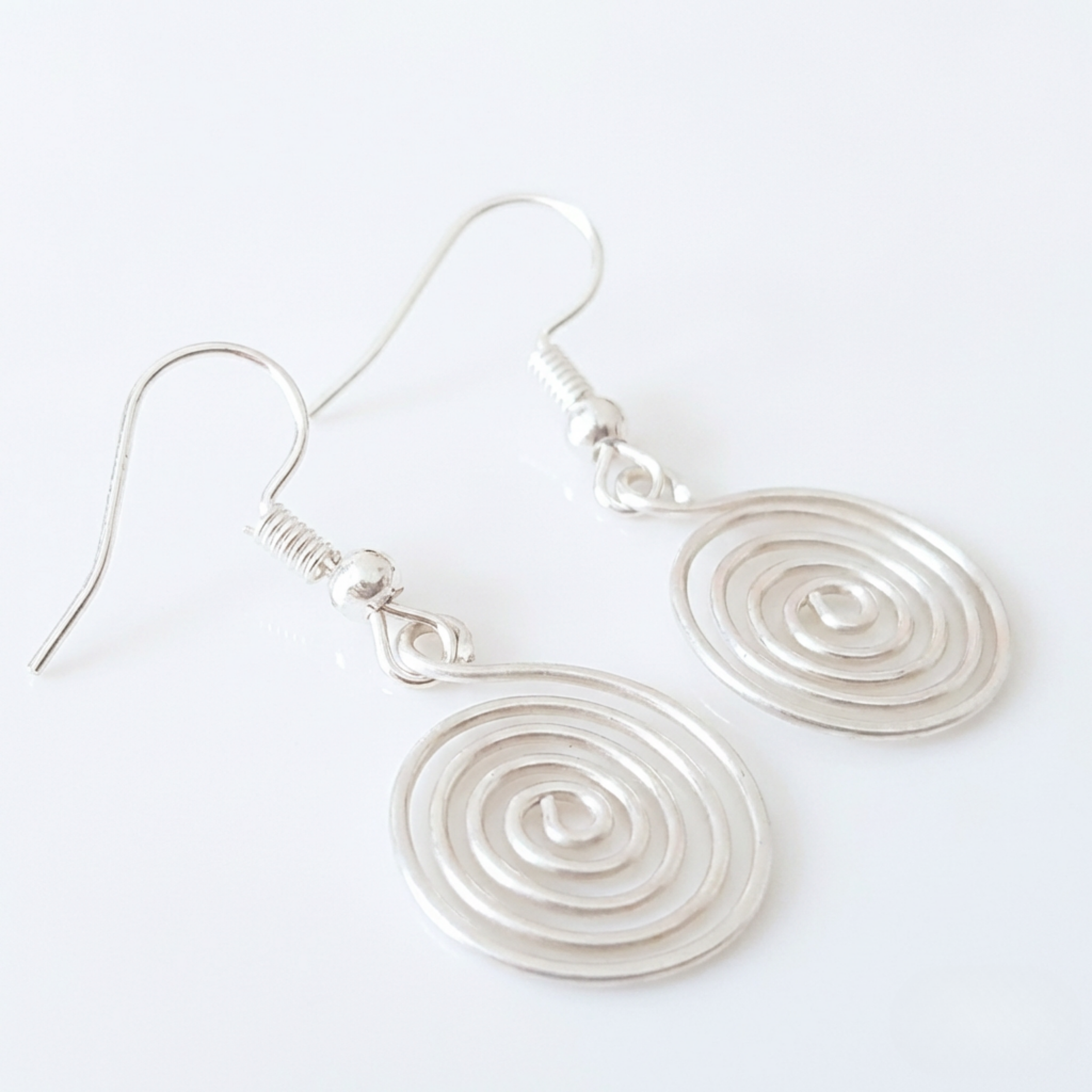 Silver spiral earrings on a white background