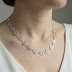 Silver spiral necklace with circular design worn by a person against a neutral background