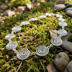 Silver spiral necklace on a bed of green moss and stones