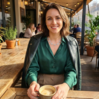 Woman sitting at an outdoor cafe holding a coffee cup wearing a silver spiral necklace