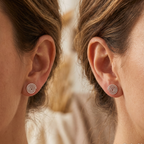 Close-up of a person wearing spiral earrings with a blurred background