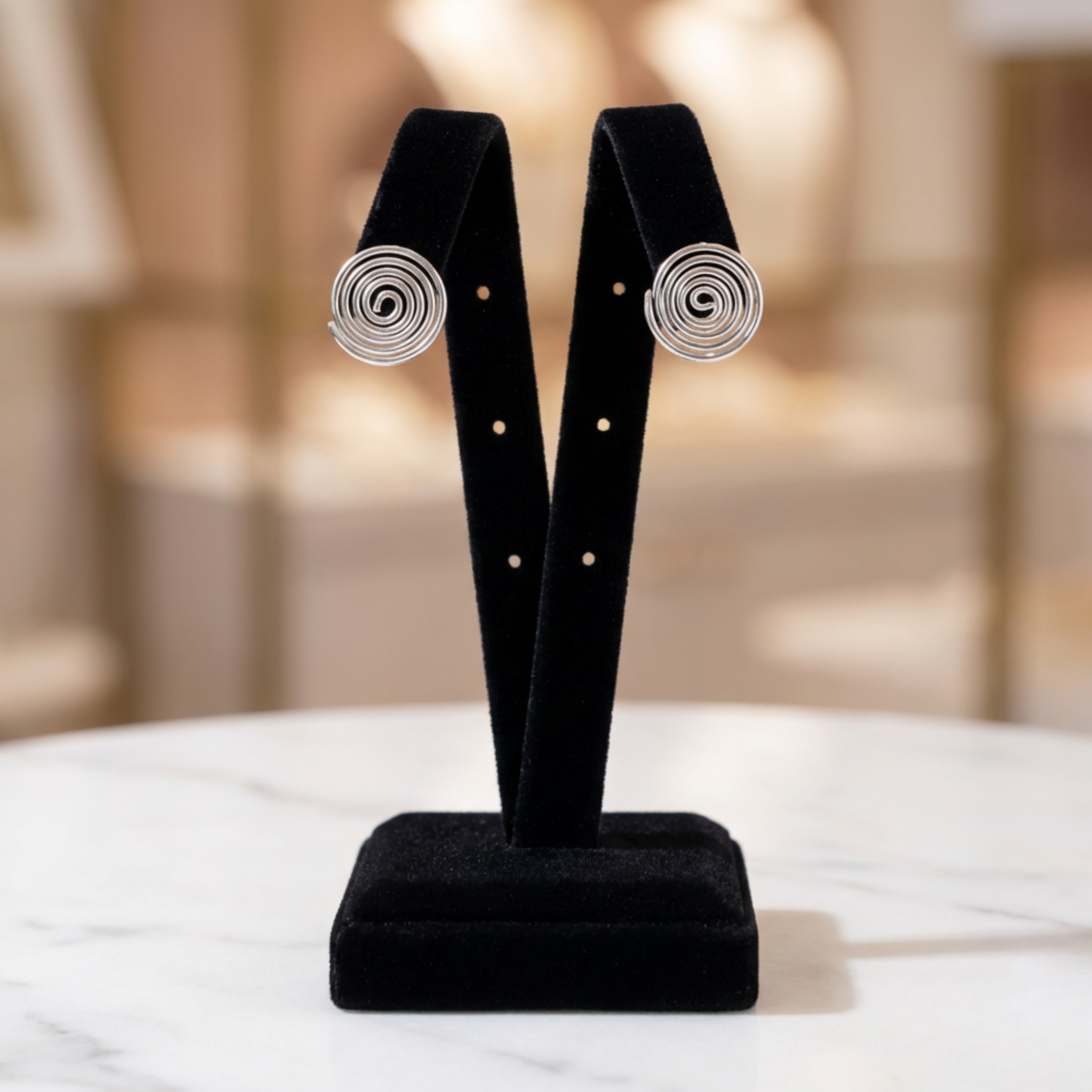 Pair of silver spiral earrings on a black velvet stand with a blurred background