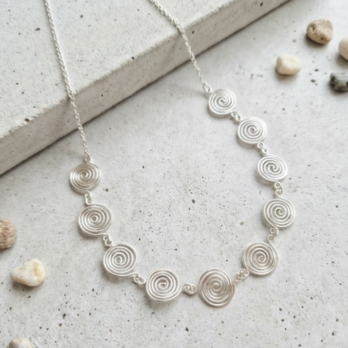 Silver necklace with circular design on a textured surface