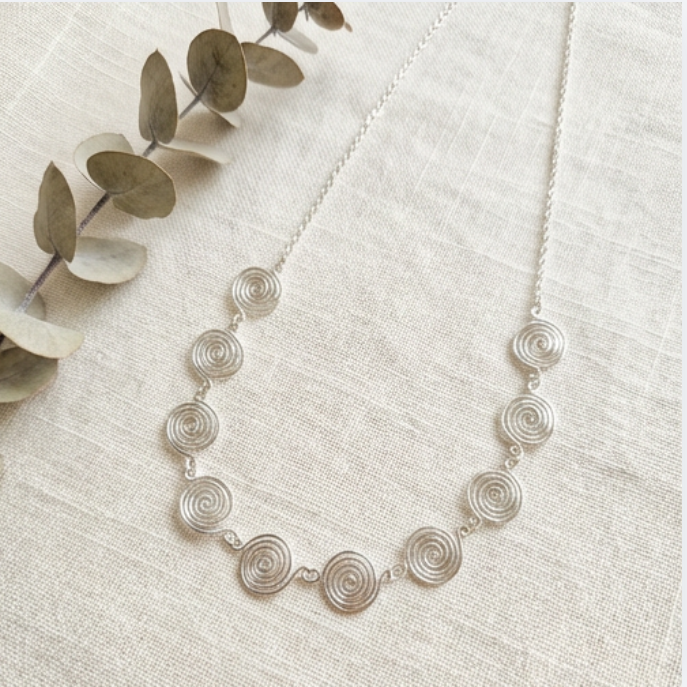 Silver necklace with circular design on a light background