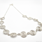 Silver necklace with circular links on a white background