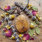 Necklace with a stone pendant on a wooden surface with dried flowers