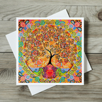 Colourful tree of life design on a card with a white envelope on a wooden surface