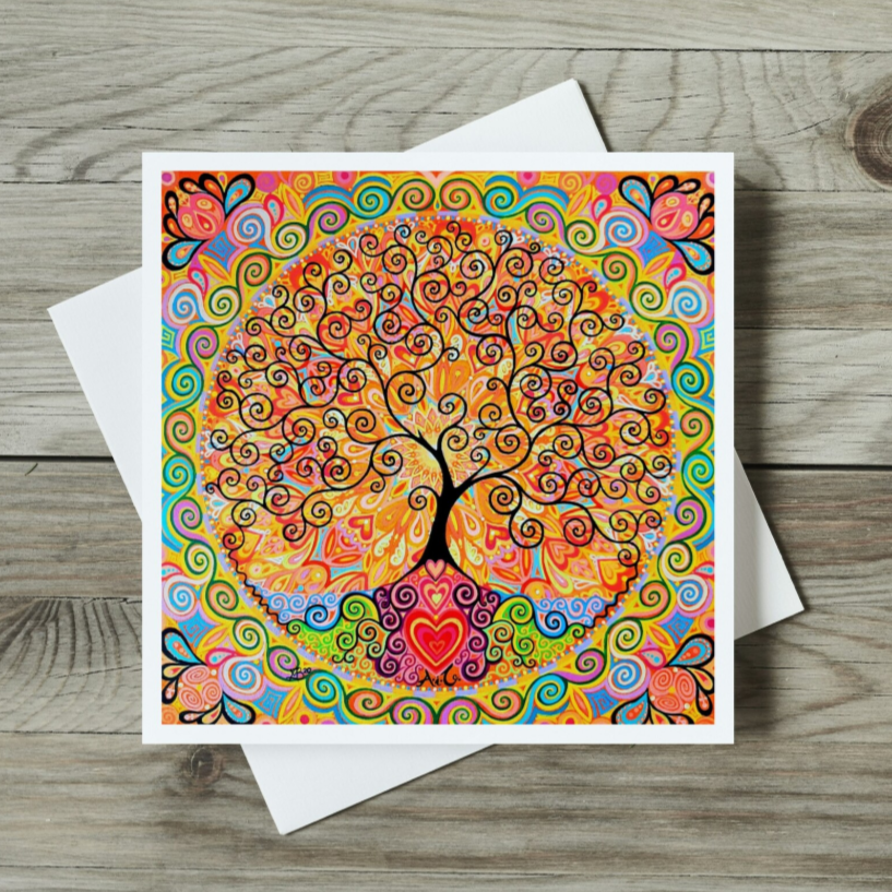 Colourful tree of life design on a card with a white envelope on a wooden surface