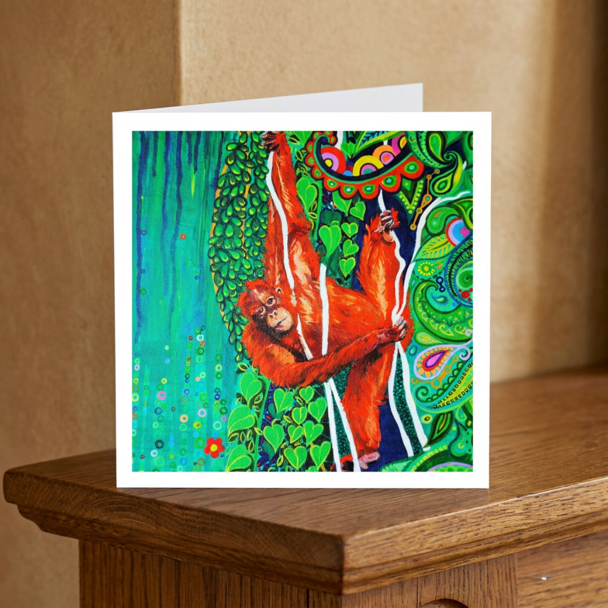 Greeting card with a colourful design of an orangutan on a wooden surface