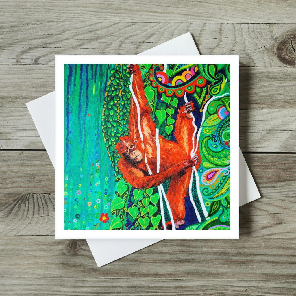 Colourful greeting card with an orange orangutan design on a wooden surface