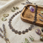 Celtic Copper Spiral necklace on a textured surface with dried lavender and stones