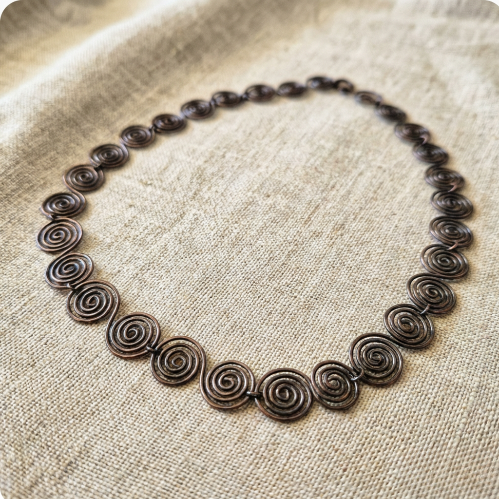Necklace with spiral design on a textured fabric background