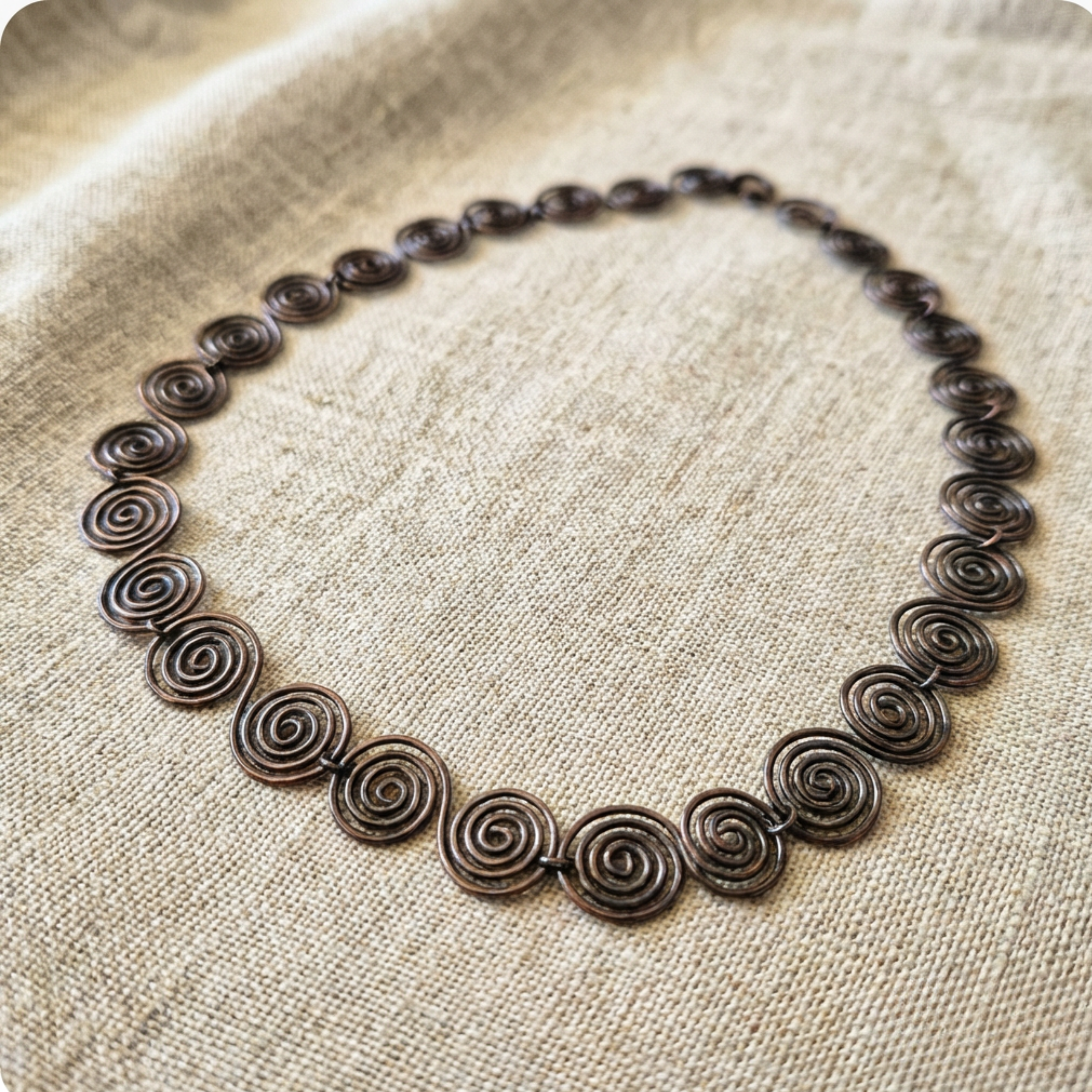 Necklace with spiral design on a textured fabric background