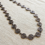 Necklace with spiral design on a beige fabric background