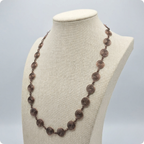 Necklace with circular spirals made in copper wire on a mannequin bust against a light grey background