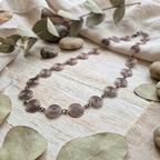 Necklace with spiral design on a natural background with leaves and stones