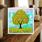 Colourful greeting card with a tree and doves design on a wooden surface.