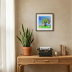 Decorative setup with a potted plant, typewriter, and framed artwork on a beige wall.