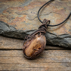 Picture Jasper pendant with copper wire wrapping on a stone and wooden surface