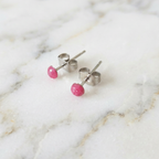 Pair of pink bead stud earrings on a marble surface