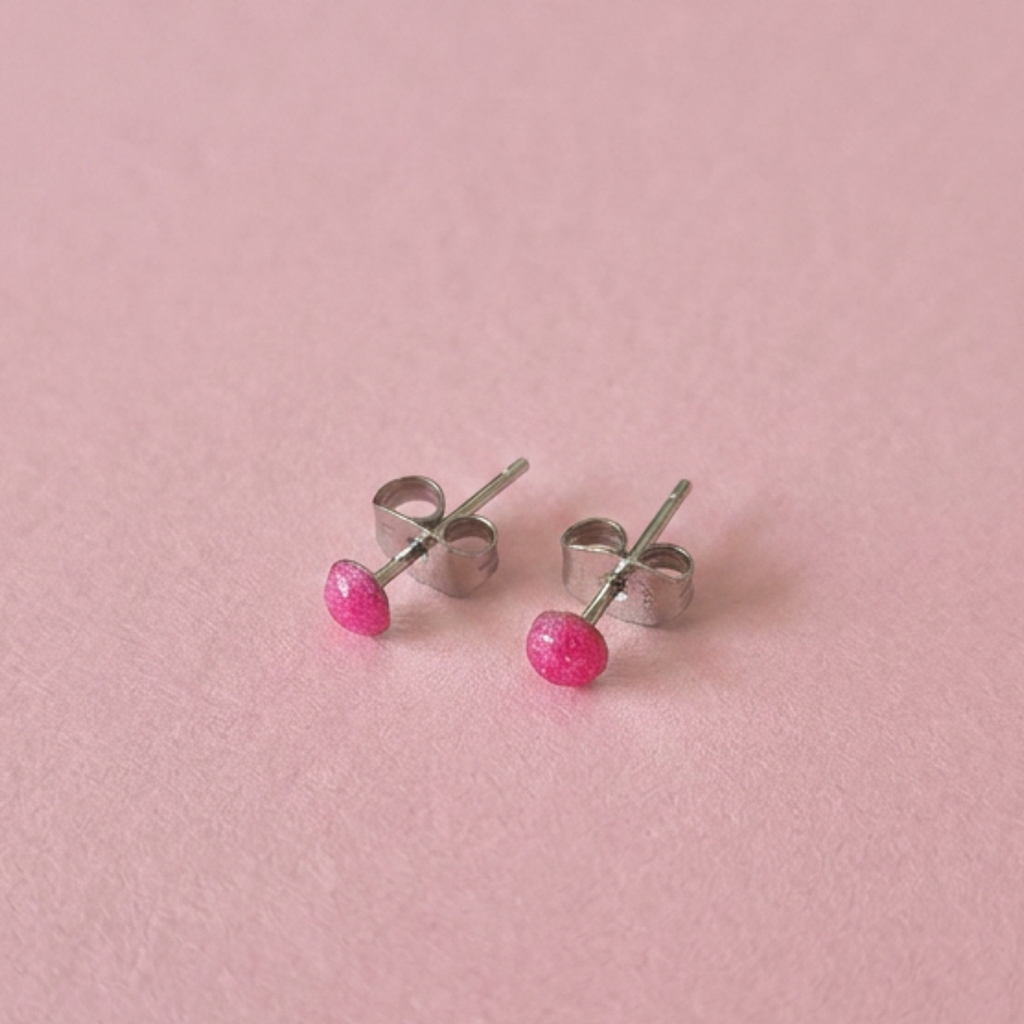 pink dot stud earrings on a pink surface
