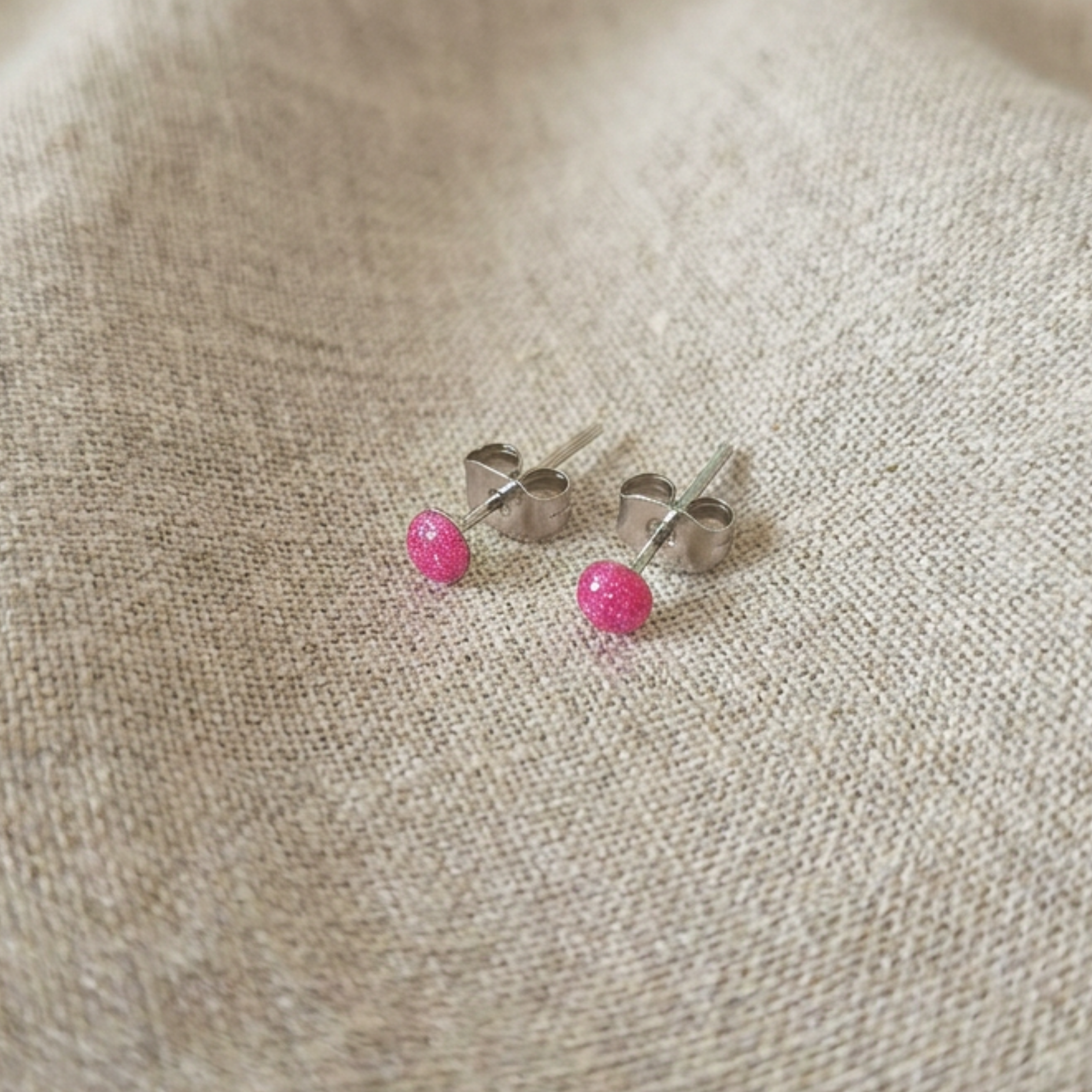 Dainty pink dot stud earrings on fabric surface