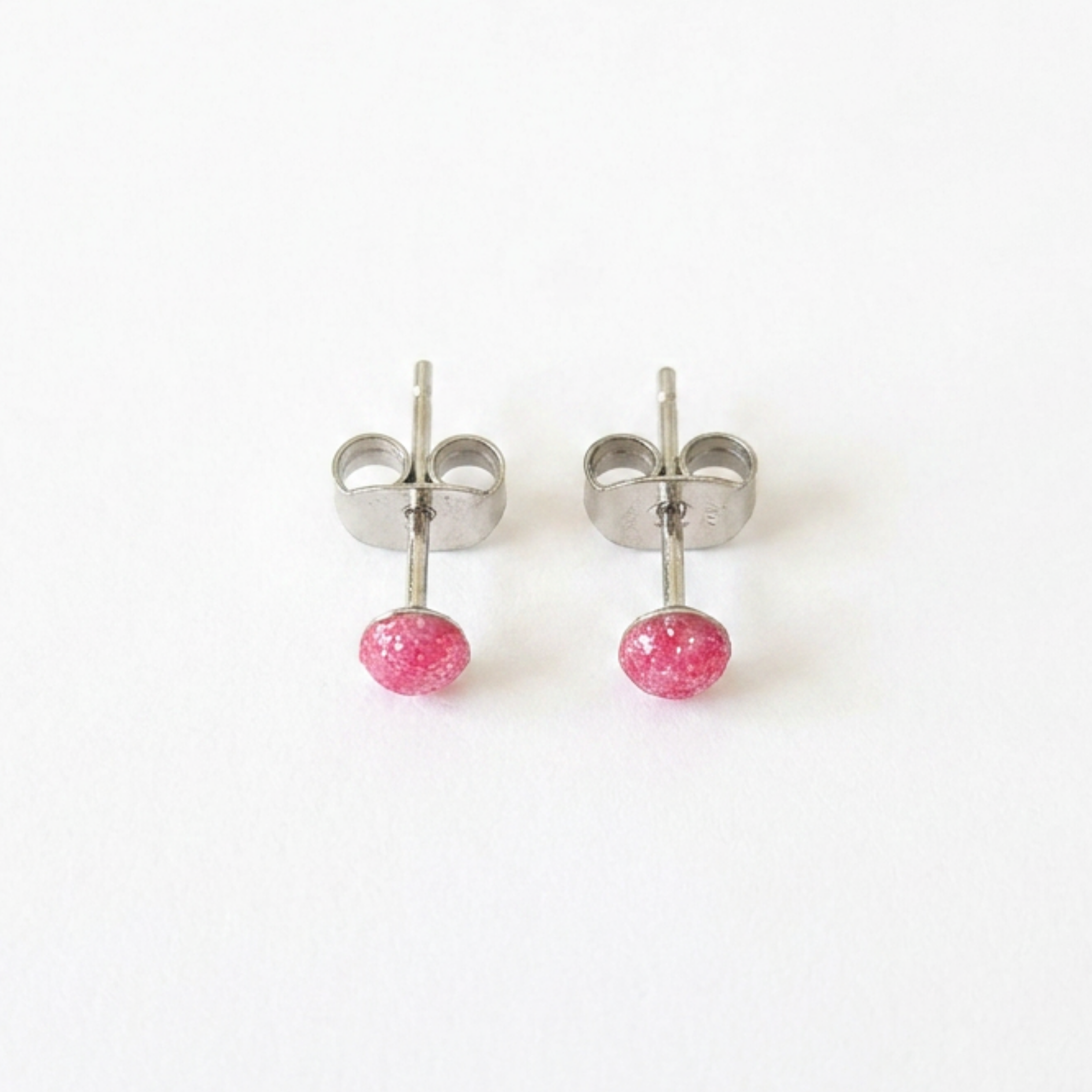 Pair of silver stud earrings with pink centre on a white background