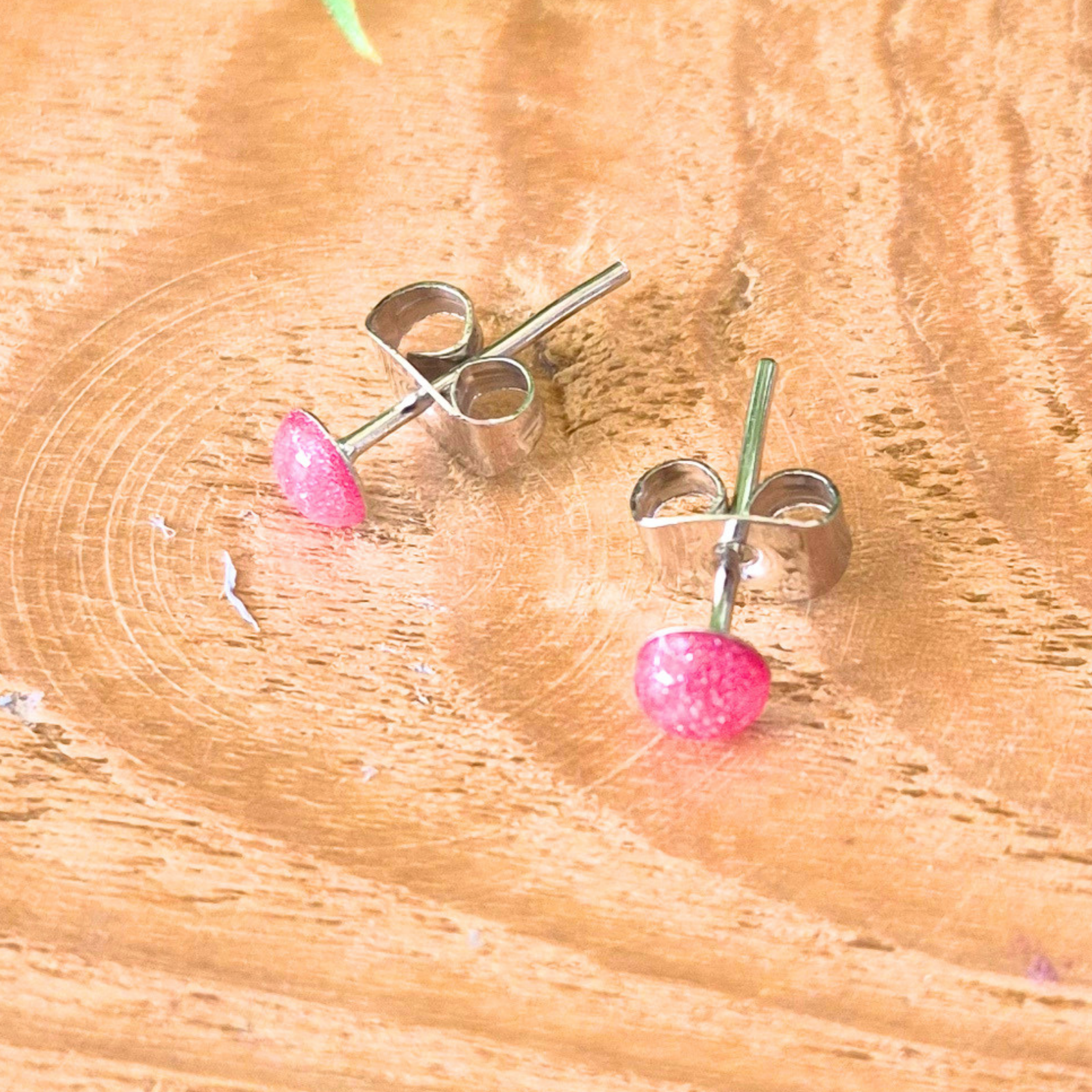 pink dot stud earrings on a wooden surface