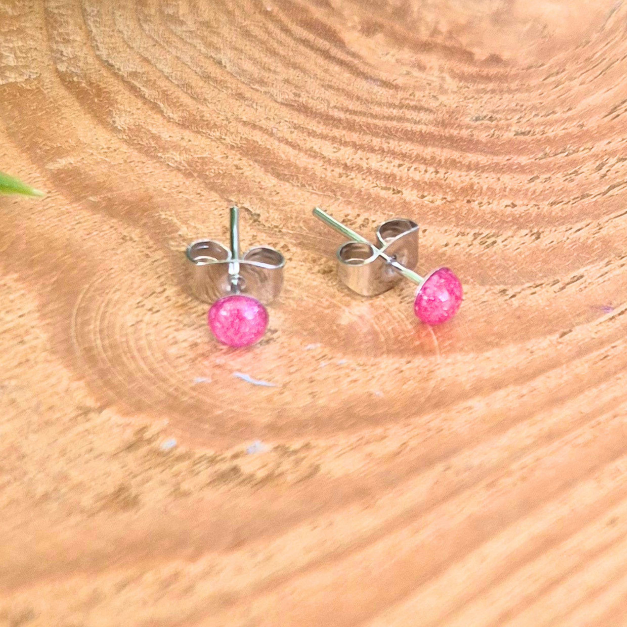 Stud earrings with 3mm pink dots on a wooden surface