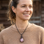 Woman wearing a necklace with a pink pendant outdoors