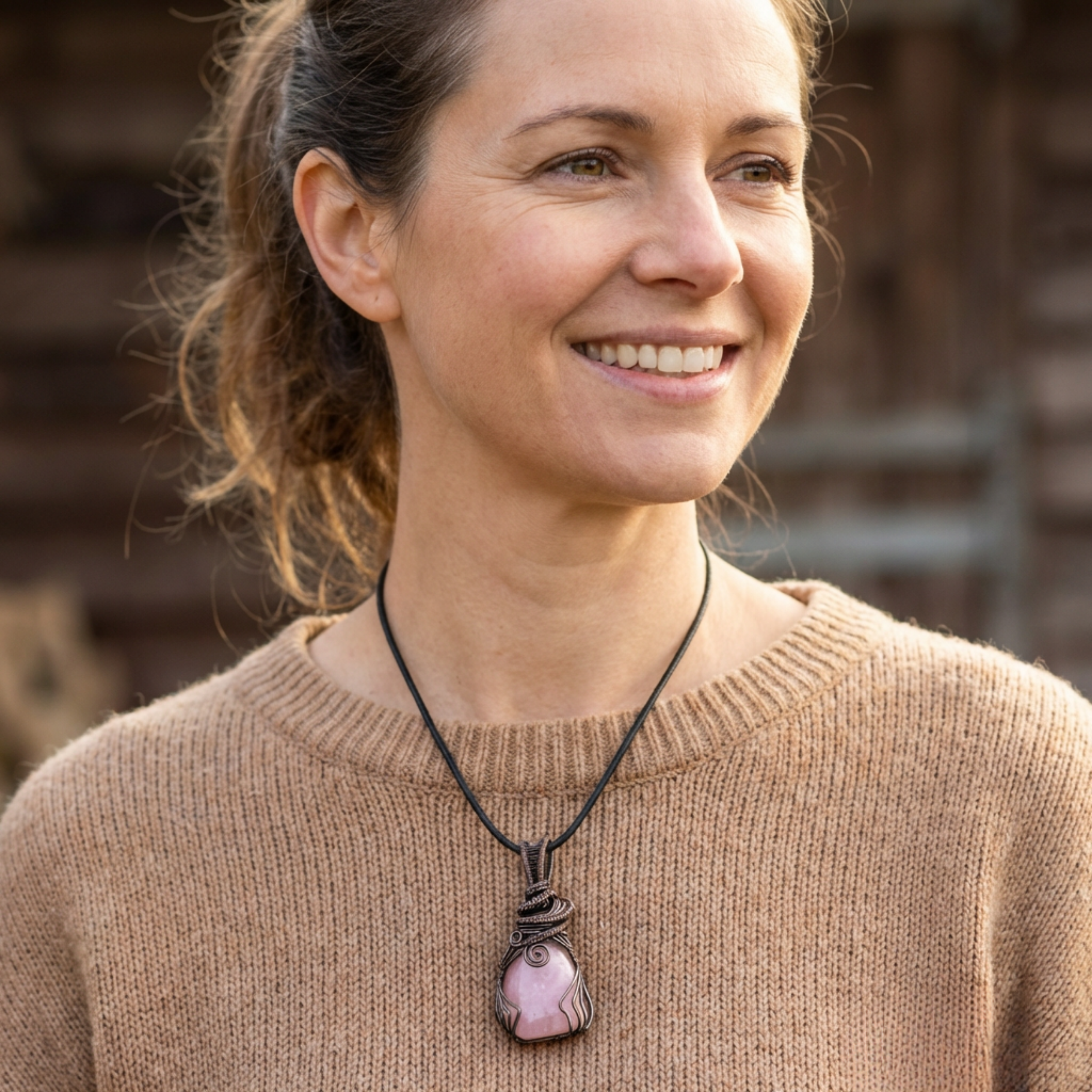 Woman wearing a necklace with a pink pendant outdoors