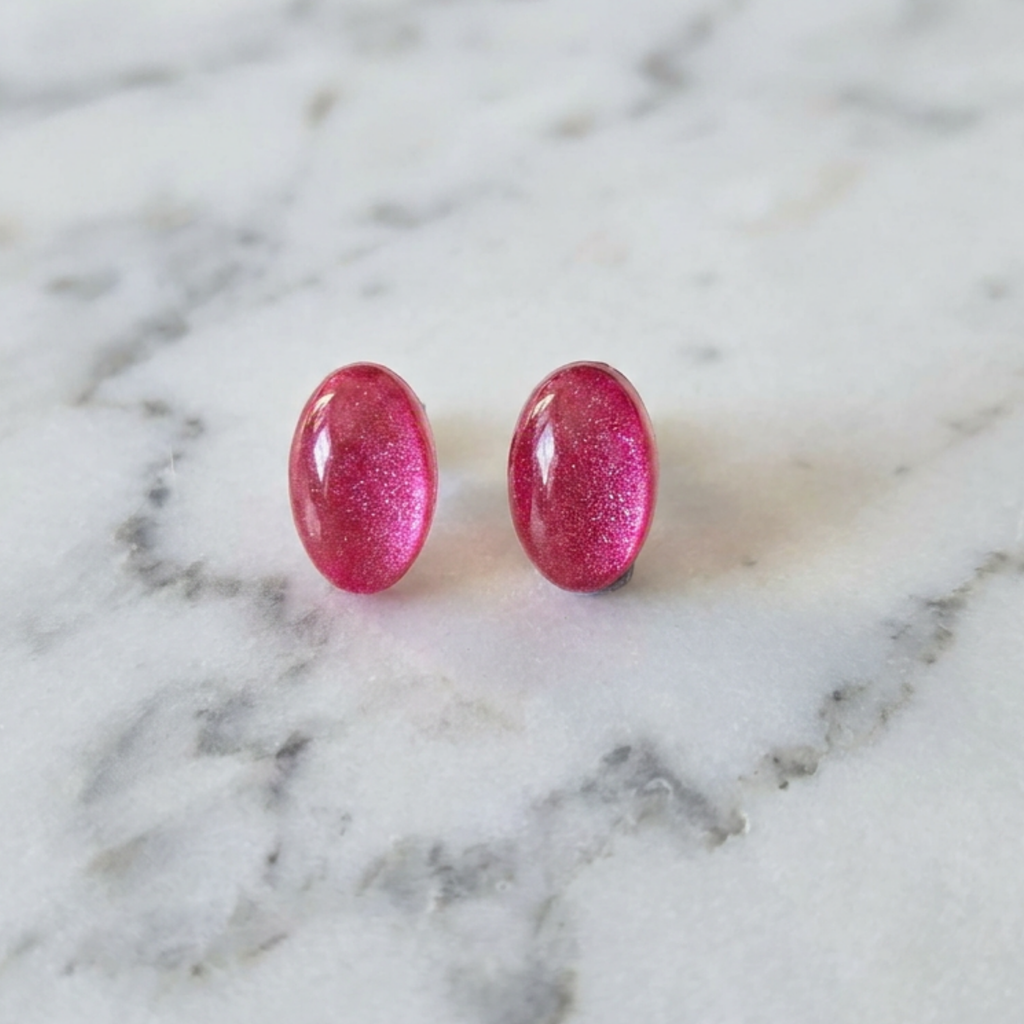 Pink glittery earrings on a marble surface