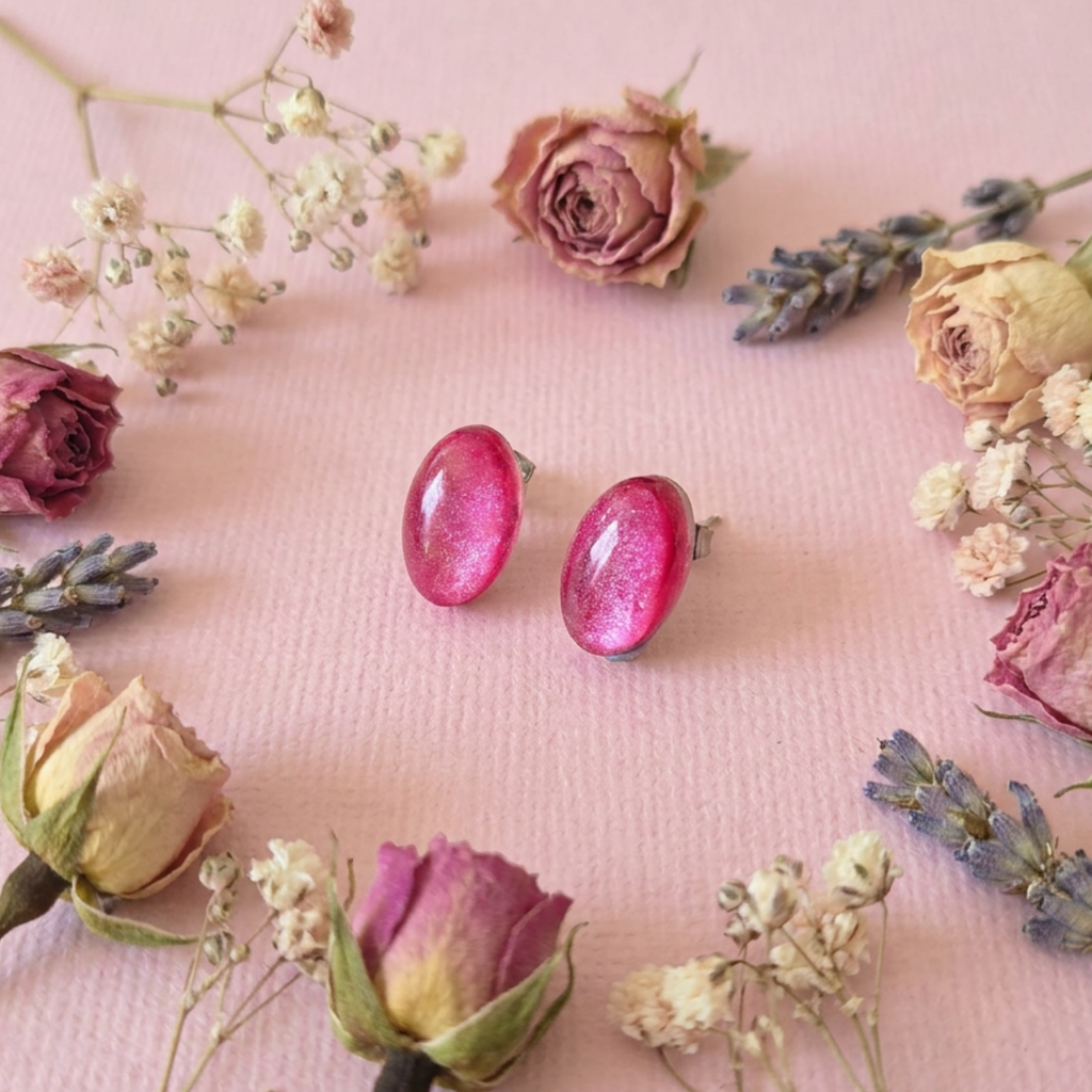 Pink earrings on a pink surface with flowers