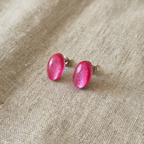 Pink oval earrings on a beige fabric background
