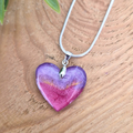 Purple and Pink shimmer heart pendant on a wooden surface
