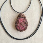 Pink and copper pendant on a fabric suface