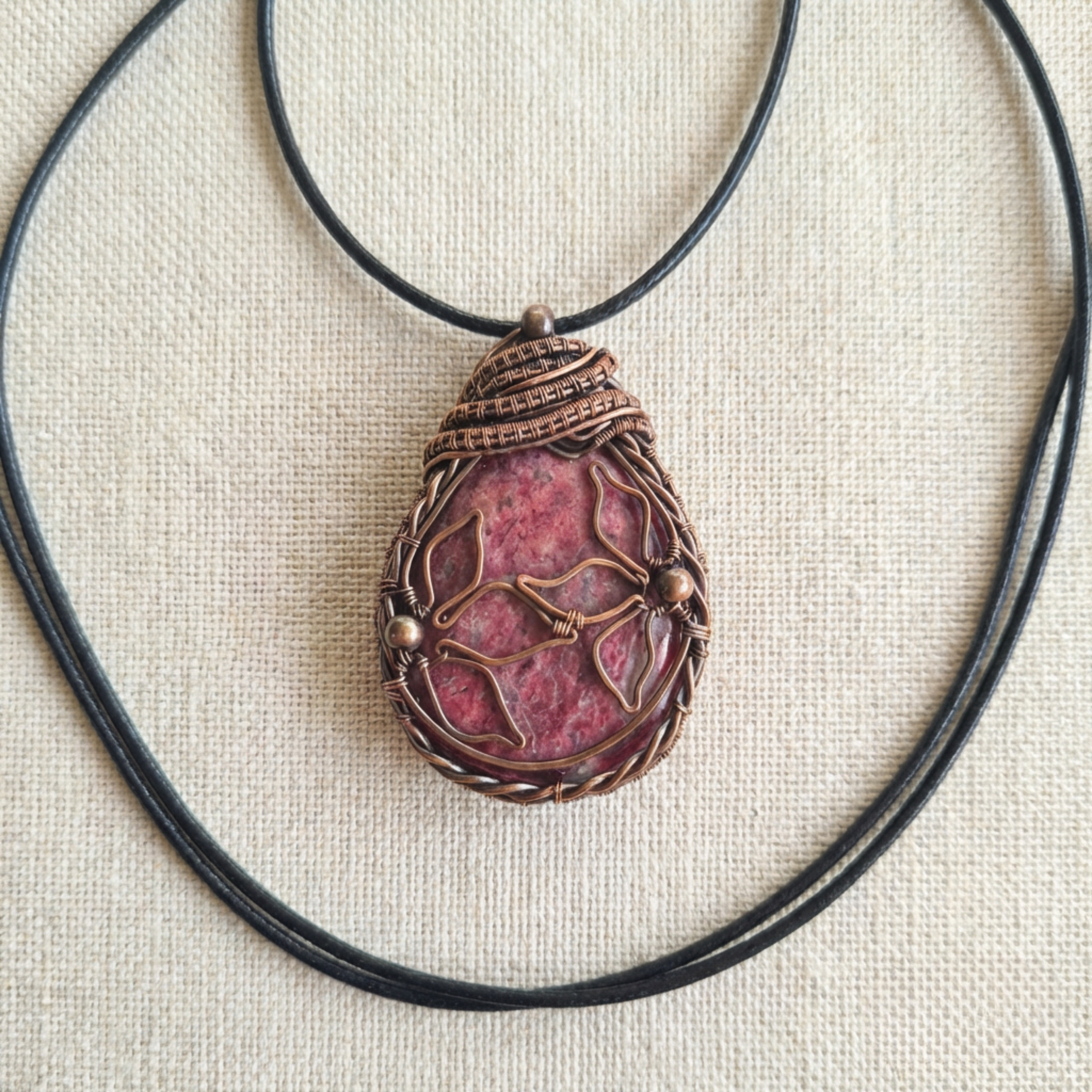 Pink and copper pendant on a fabric suface