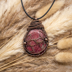 Pink and copper stone pendant on a grass background