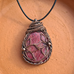 An intricate copper wire wrapped pendant with a Rhodonite gemstone