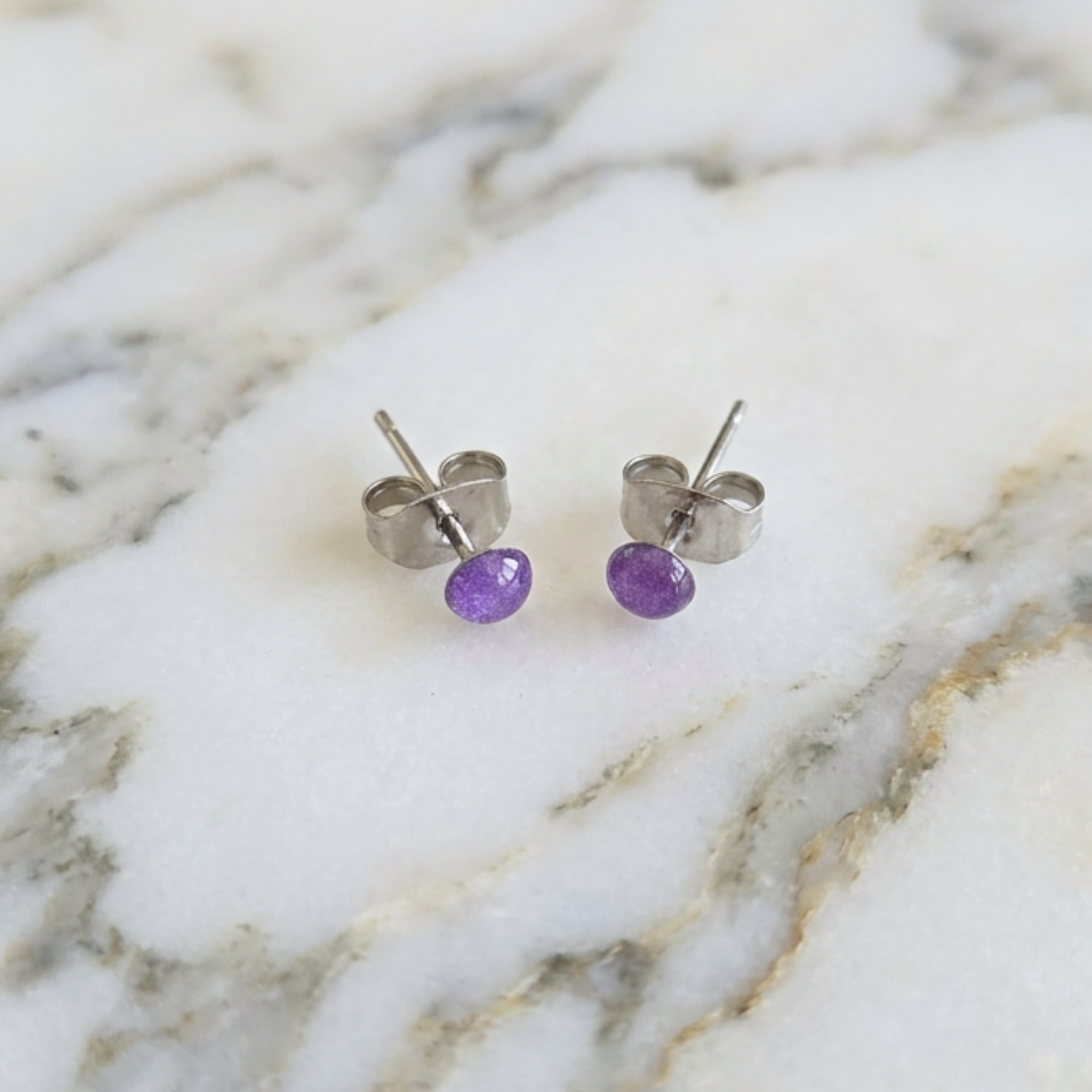 Purple resin stud earrings on a marble surface
